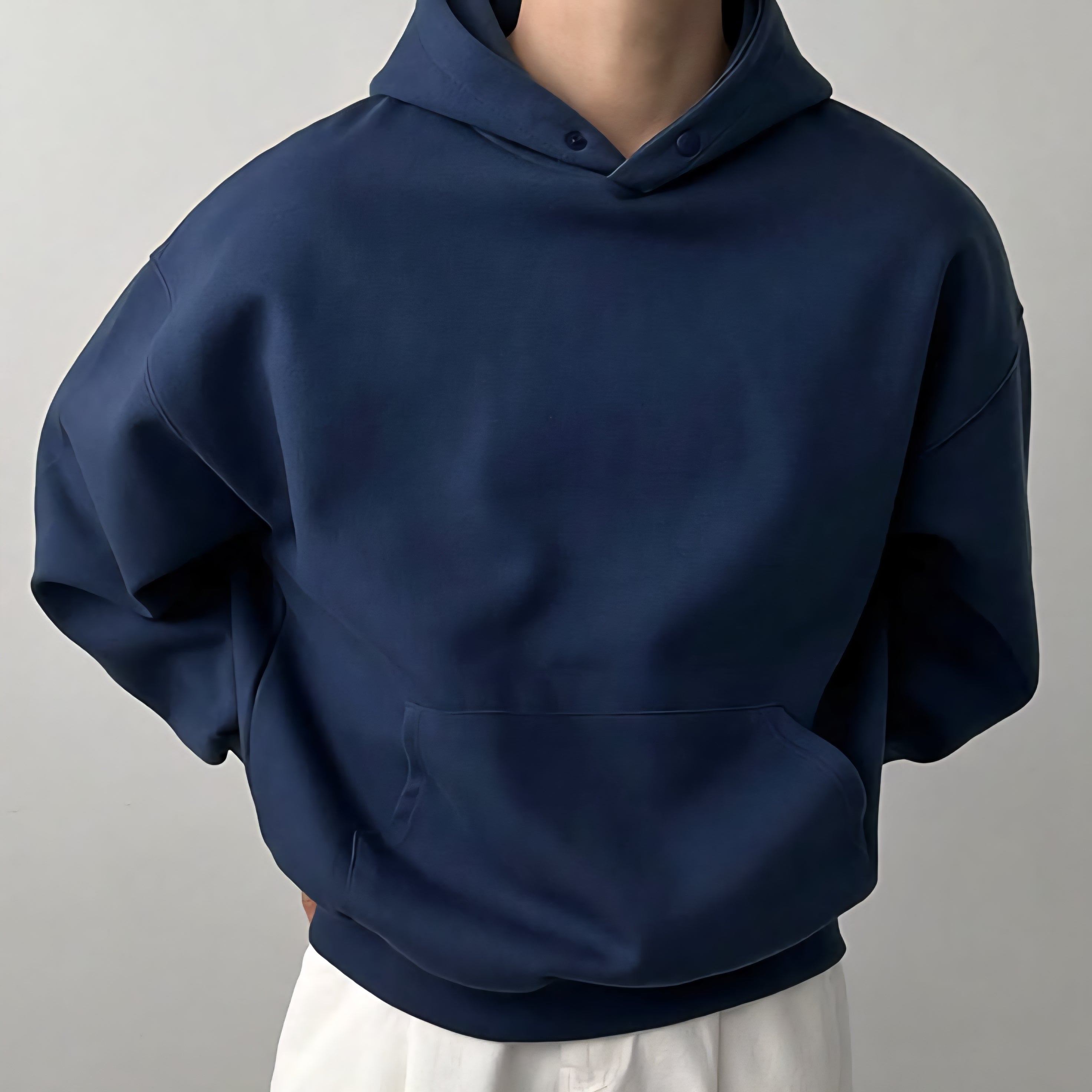 Navy blue hoodie worn by a person on a gray background